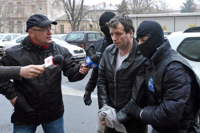 Marcel Lazar Lehel, 40, is escorted by masked policemen in Bucharest, after being arrested in Arad, 550 km (337 miles) west of Bucharest January 22, 2014. REUTERS/Mediafax/Silviu Matei